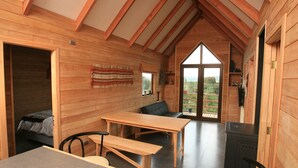 Ein gemütliches Holzhaus mit Essbereich, einer Couch und Blick ins Freie.
