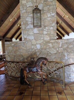 Cozy retreat with a high ceiling, wooden beams, and a stone wall, featuring a decorative bench and a hanging lantern.