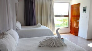 Une chambre d’hôtel avec deux lits, une fenêtre avec des rideaux et une porte en bois.