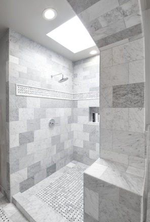 A modern shower with a skylight, marble tiles, and a perforated floor. - Rockhouse Suites (Healdsburg)