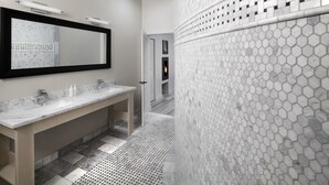 A modern bathroom with a large mirror, two sinks, and a shower area with a hexagonal tile pattern. - Rockhouse Suites (Healdsburg)