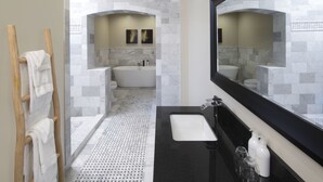 A modern bathroom with a freestanding bathtub, a large mirror, and a black countertop. - Rockhouse Suites (Healdsburg)