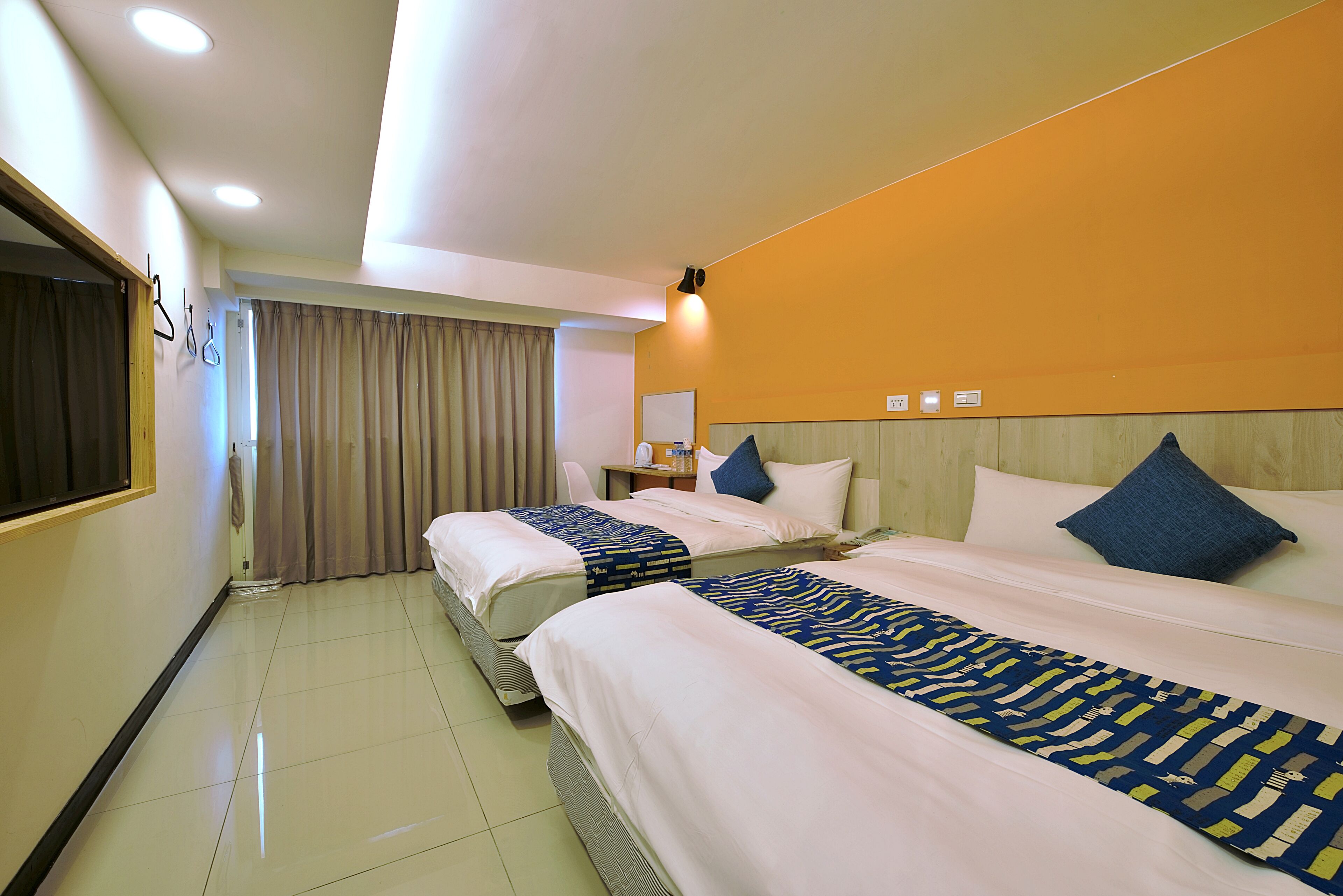 Quarto de hotel com duas camas, uma mesa e uma cadeira.
