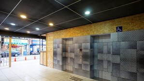 A modern elevator area with a wooden panel wall and metal lockers. - Good Night Hotel (Taoyuan City)