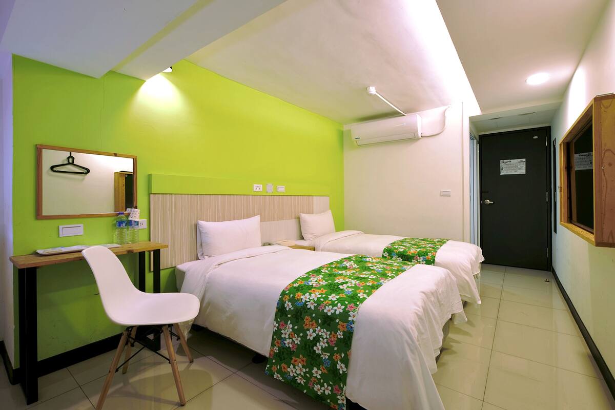Une chambre avec deux lits, un bureau, une chaise et un appareil de climatisation.