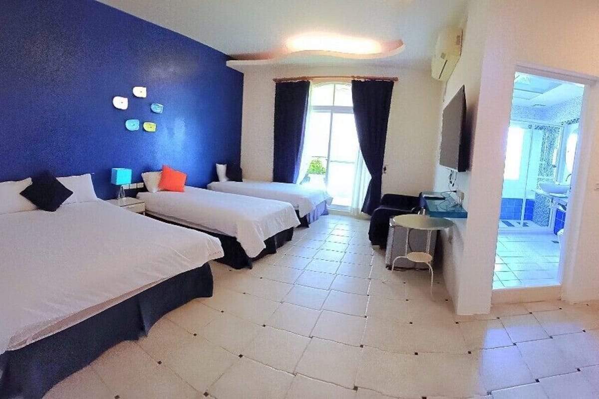 A hotel room with two beds, a desk, a TV, and a wardrobe.