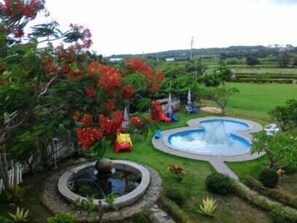 A garden with a circular water feature, a small pond, and a variety of plants and trees. - Bohemian Holiday Inn (Hengchun)
