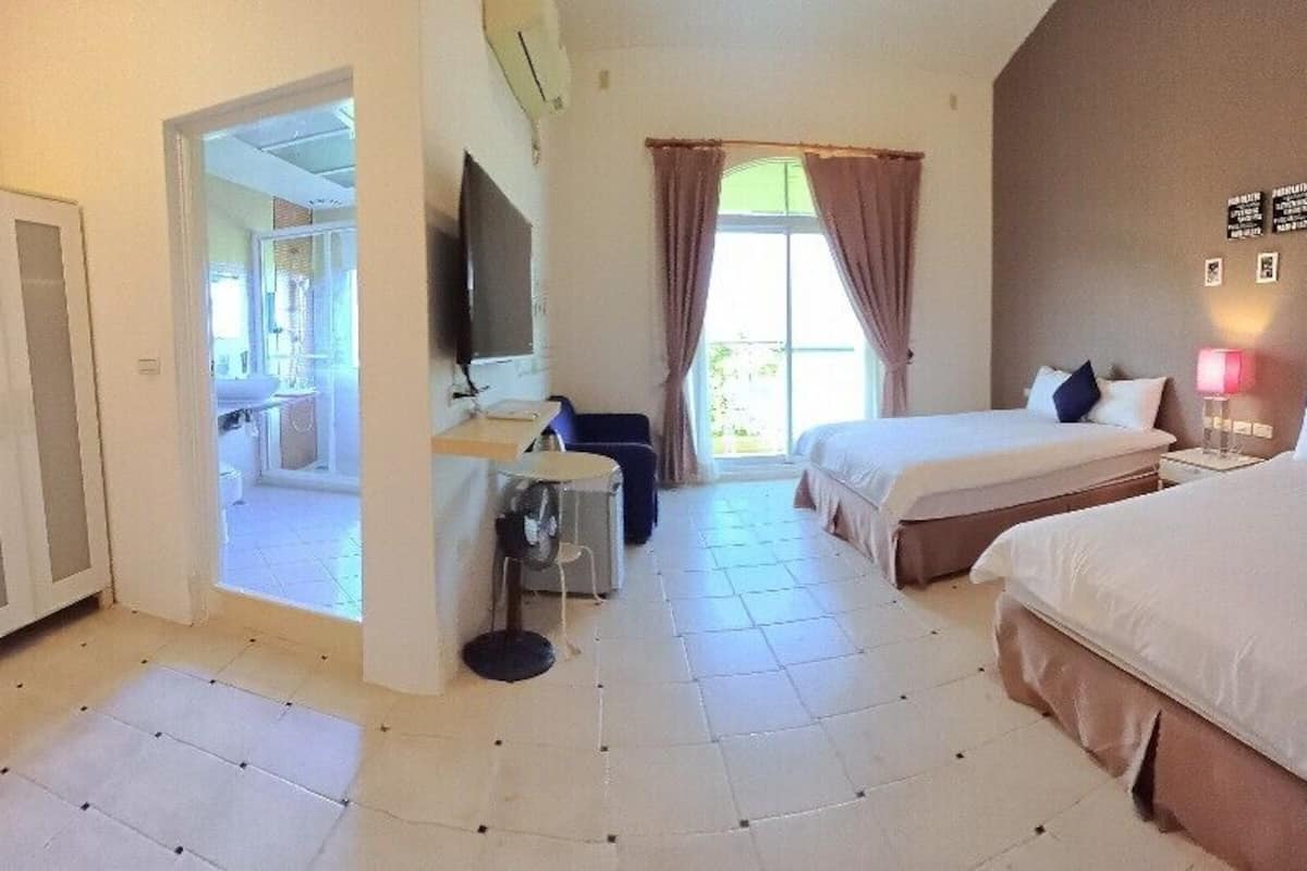 A hotel room with two beds, a desk, a chair, a wardrobe, and a television.