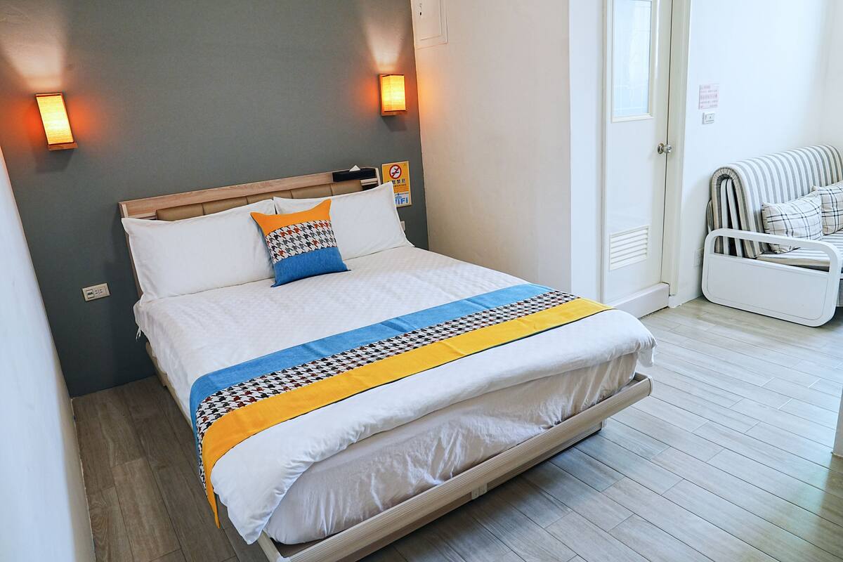 A neatly made bed with a patterned blanket, two pillows, and a headboard.