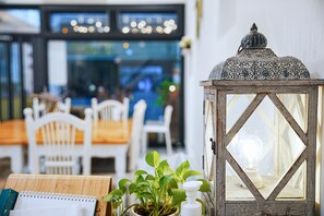Un ambiente interior acogedor con una mesa de madera, sillas, una planta en maceta y un farol decorativo.