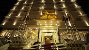 A hotel entrance with a sign reading "REST NIGHT" and multiple flags. - Rest Night Serviced Apartments  Wadi Al Dawasir رست نايت للشقق المخدومة - وادى الدواسر (Wadi-Ad-Dawasir)