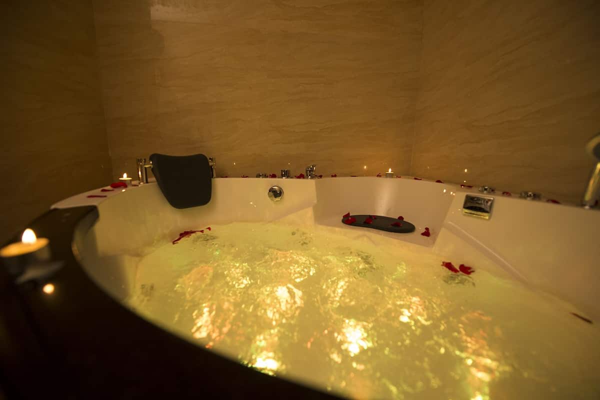 Ett bubbelbad med rosenblad och ljus, vilket skapar en romantisk atmosfär.
