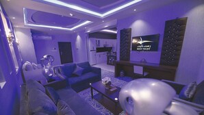 A modern hotel room with a sofa, armchairs, a coffee table, a TV, and a sign indicating a rest area. - Rest Night Serviced Apartments  Wadi Al Dawasir رست نايت للشقق المخدومة - وادى الدواسر (Wadi-Ad-Dawasir)