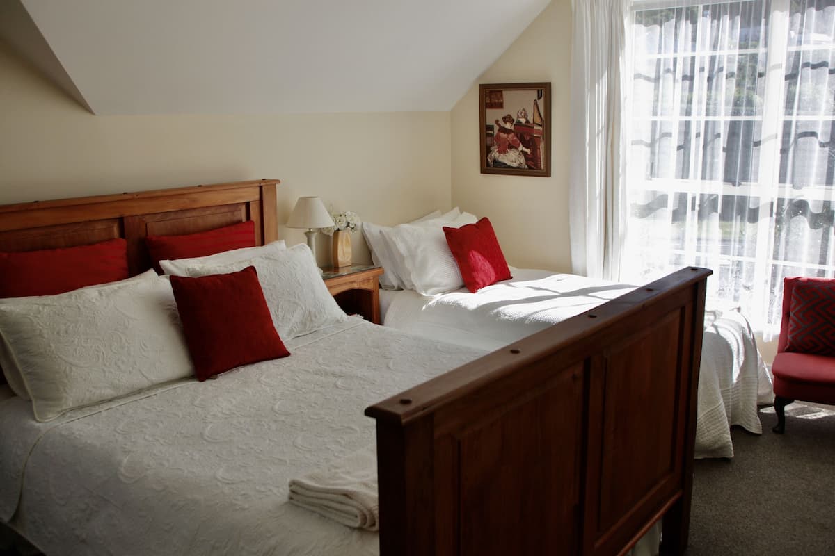 A double bed with a wooden headboard, two nightstands, and a red chair.
