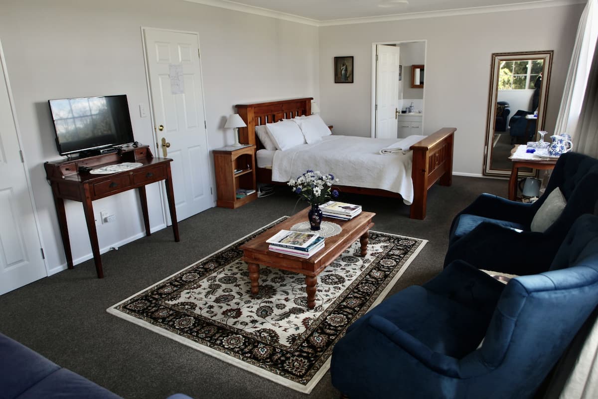 A hotel room with a bed, a television, a desk, a chair, and a coffee table.