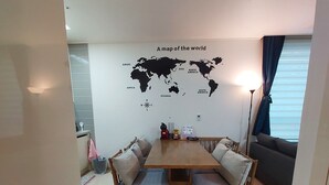 Un comedor con mesa y sillas de madera, un mapa mundial en la pared y una ventana con cortinas.
