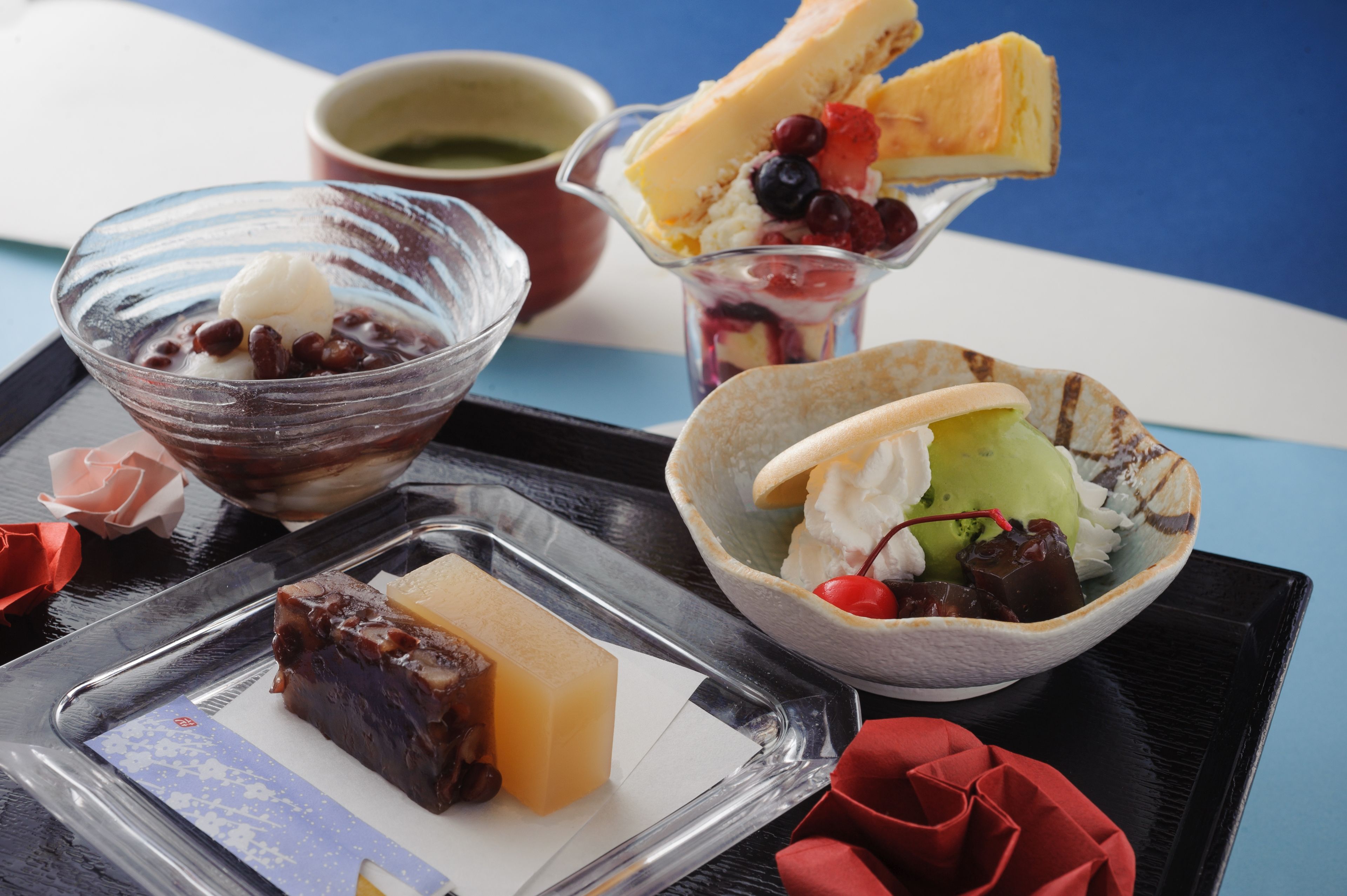 A tray with various desserts including a slice of cake, bowls of ice cream with fruits, and a small bowl of green ice cream.