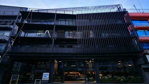 A modern building with a glass facade, multiple balconies, and a visible entrance with a sign. - Sook Station (Bangkok)