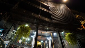 A modern building with a curved facade, large windows, and hanging plants. - Sook Station (Bangkok)