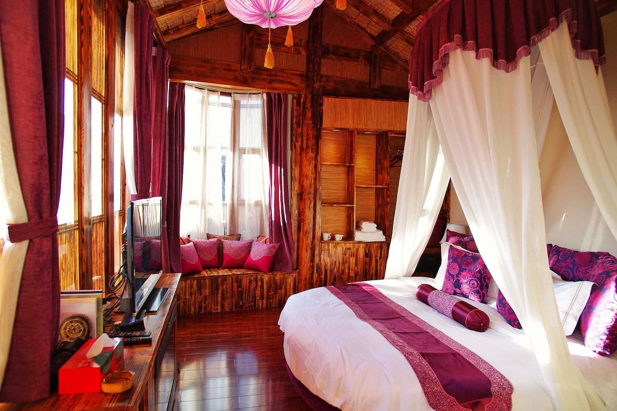A wooden room with a bed, a desk, and a window.