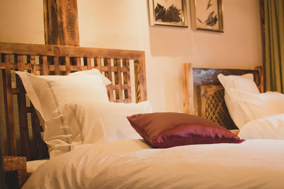 A double bed with white and brown pillows, a wooden headboard, and a nightstand.