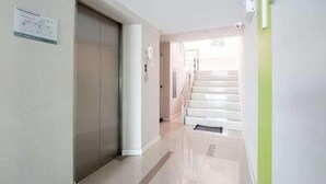 A clean, modern hallway with a staircase leading to an upper floor. - Krit Place (Nonthaburi)