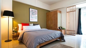 Ein modernes Schlafzimmer mit einem großen Bett, einem Nachttisch, einer Lampe, einem Kleiderschrank und Blick ins Freie.