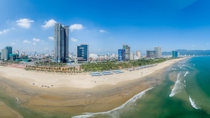 Un paisaje urbano costero con rascacielos, una playa de arena y un cielo azul despejado.