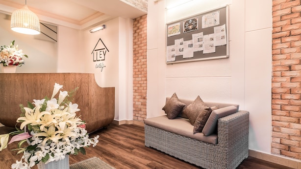 A reception area with a wicker sofa, a bulletin board, and a reception desk. - Alleyway Hostel - Adults Only (Ho Chi Minh City)