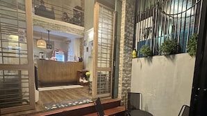 A restaurant with a wooden floor, outdoor seating, and a view through large glass doors. - Alleyway Hostel - Adults Only (Ho Chi Minh City)