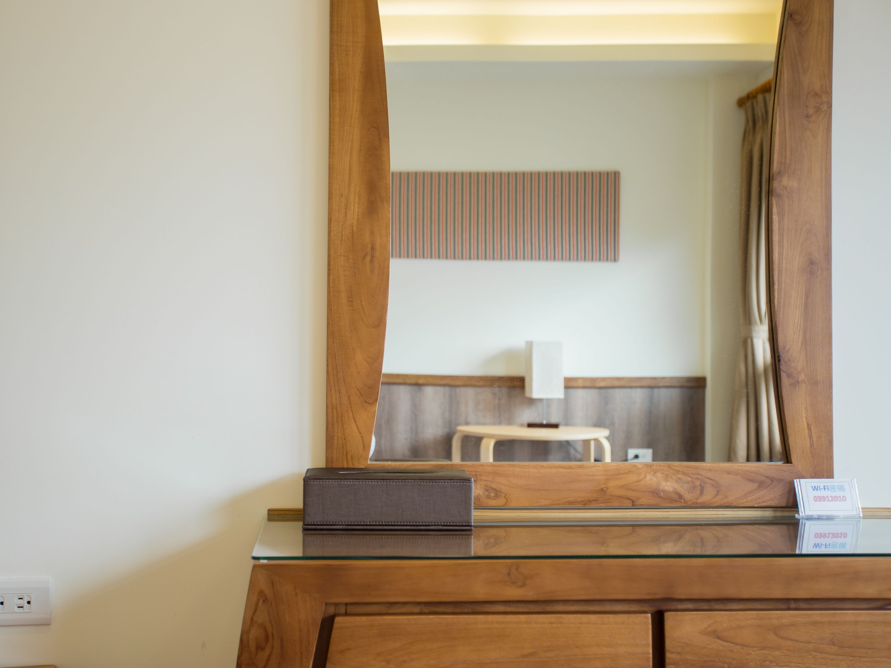 Una tocador de madera con superficie de vidrio, un espejo y un cartel de Wi-Fi.