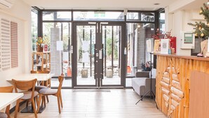 Un interior moderno con una mesa de recepción, sillas de madera y una puerta de vidrio que da al exterior.