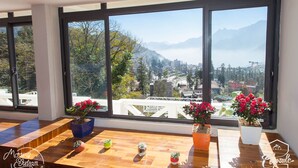 Una mesa de madera con plantas en macetas en una habitación con grandes ventanales que dan a una ciudad y montañas.