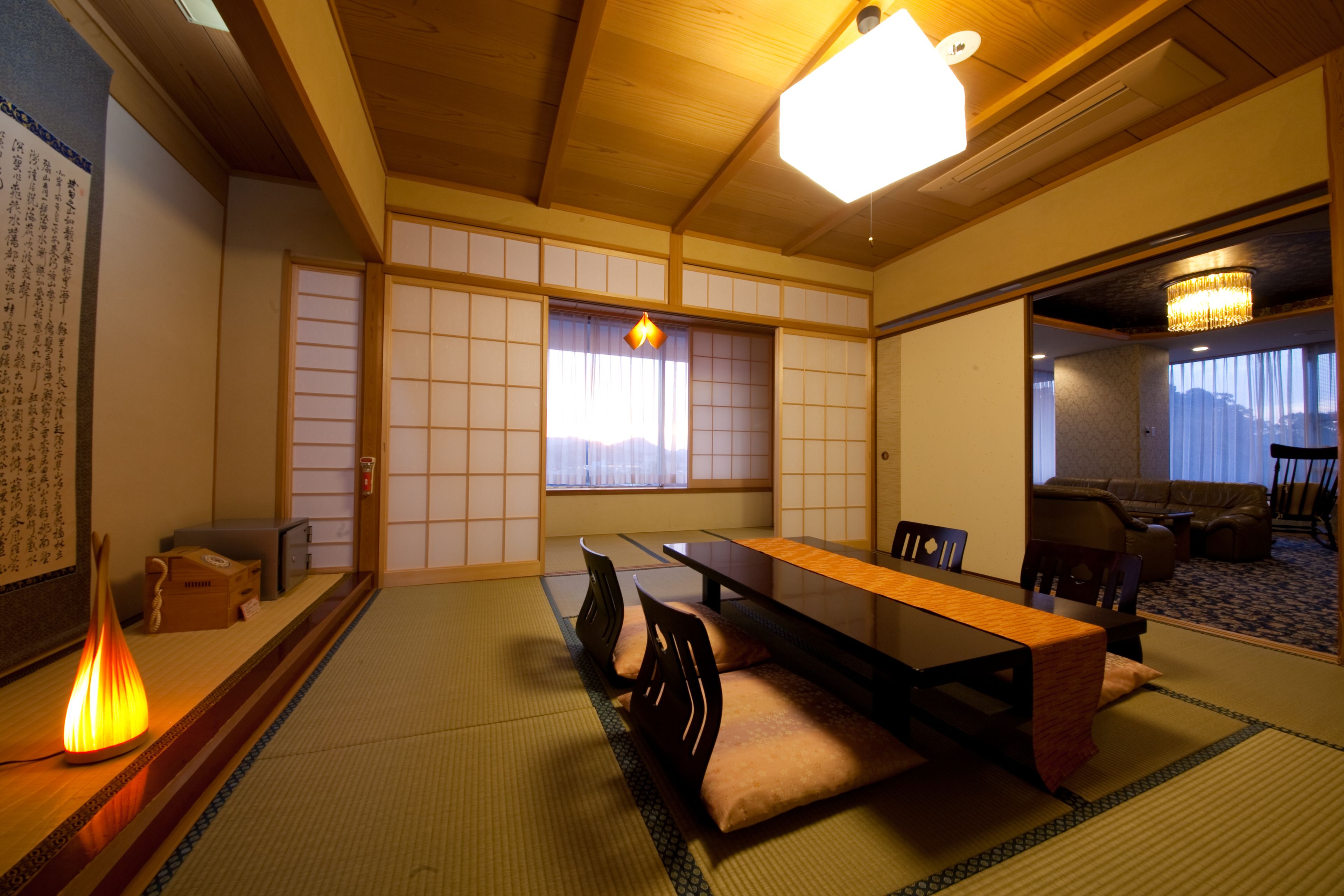 Una habitación japonesa tradicional con suelo de tatami, una mesa baja con cojines y puertas correderas shoji.