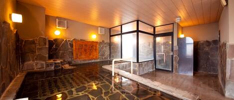 A stone-floored indoor pool with a wooden ceiling and stone walls.