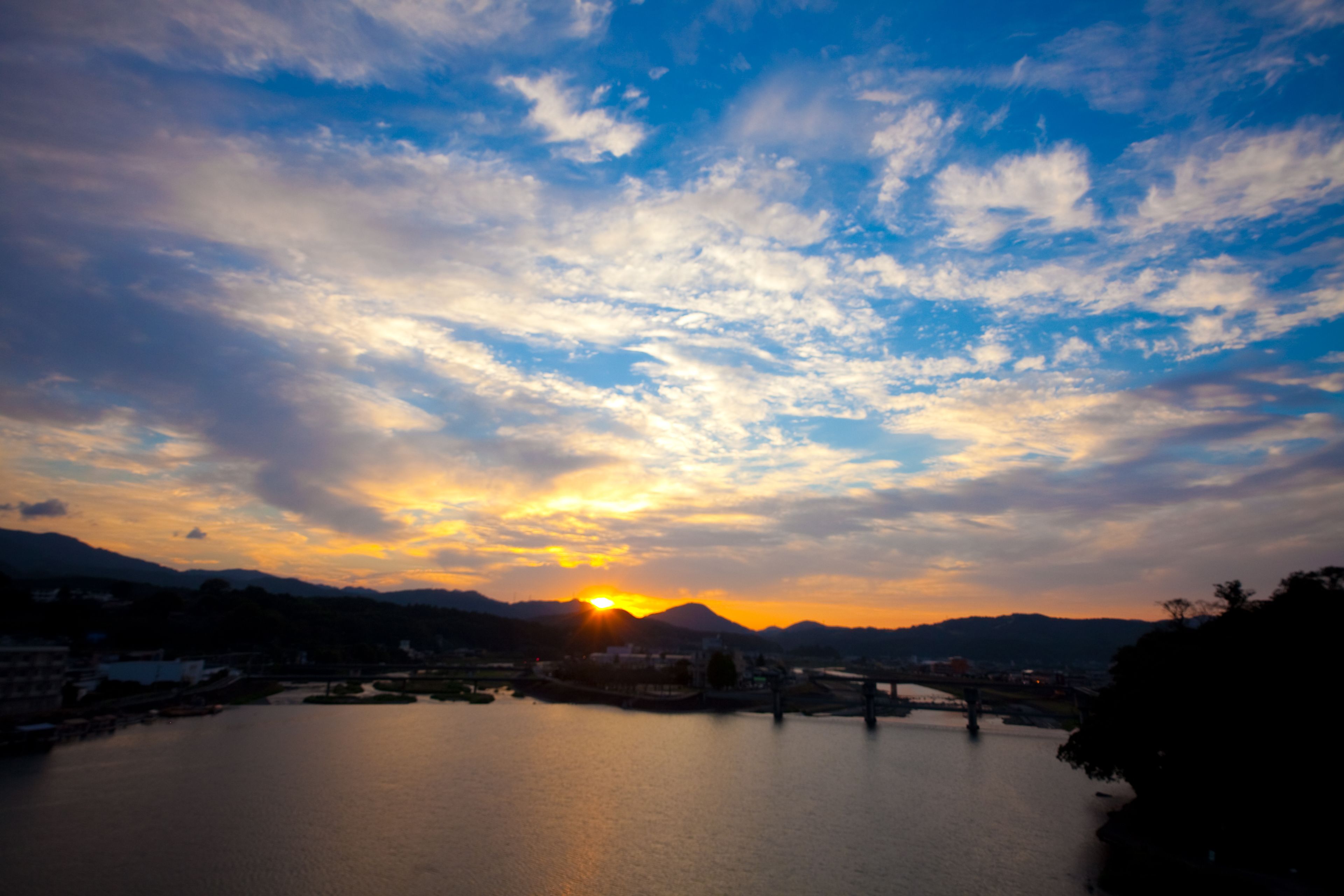 A sunset over a calm river with mountains in the background.