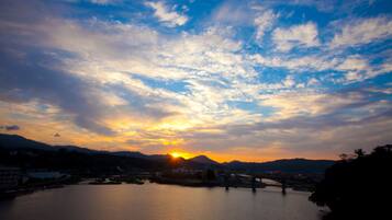A sunset over a calm river with mountains in the background.
