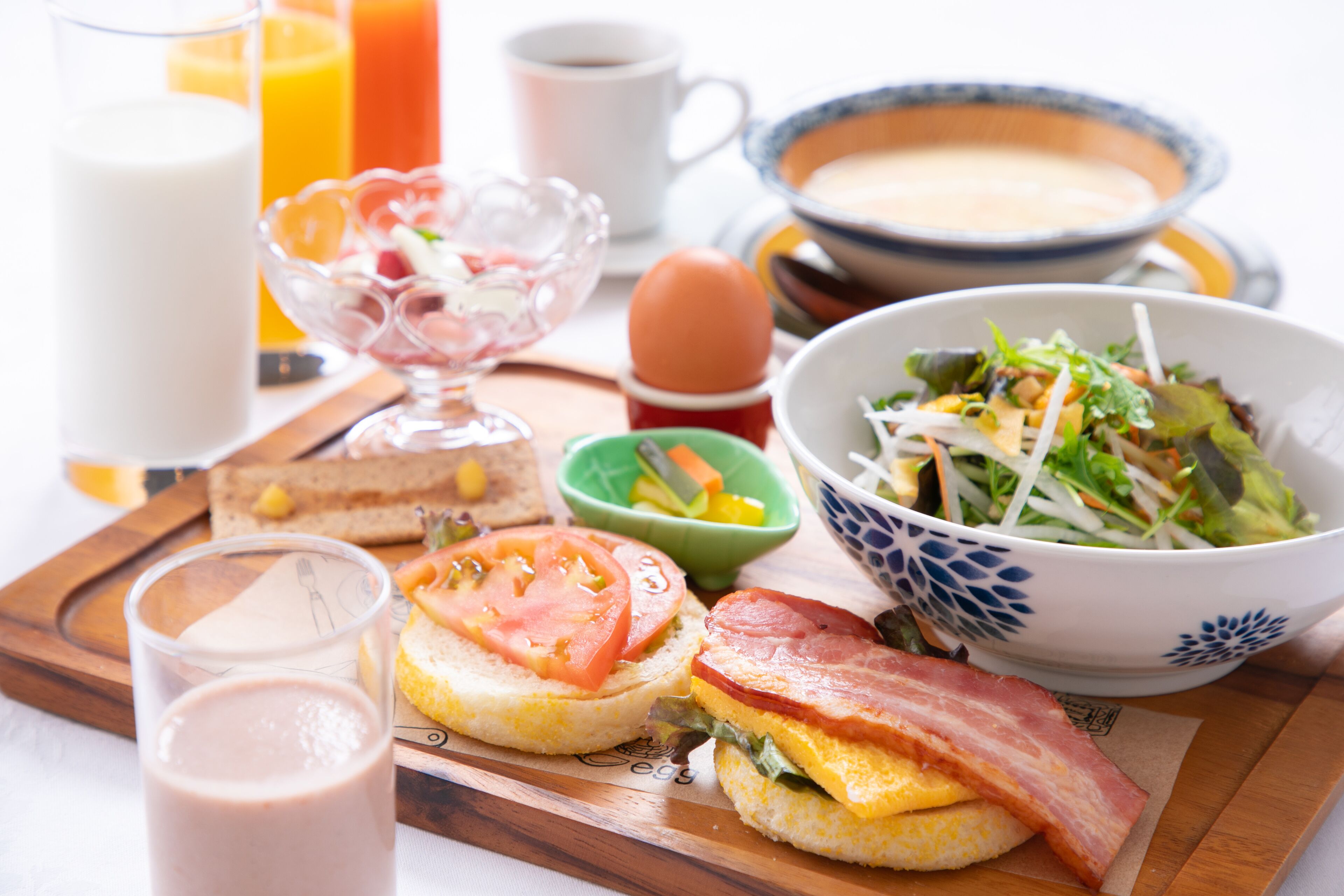 A breakfast tray with eggs, bacon, toast, and a bowl of salad.