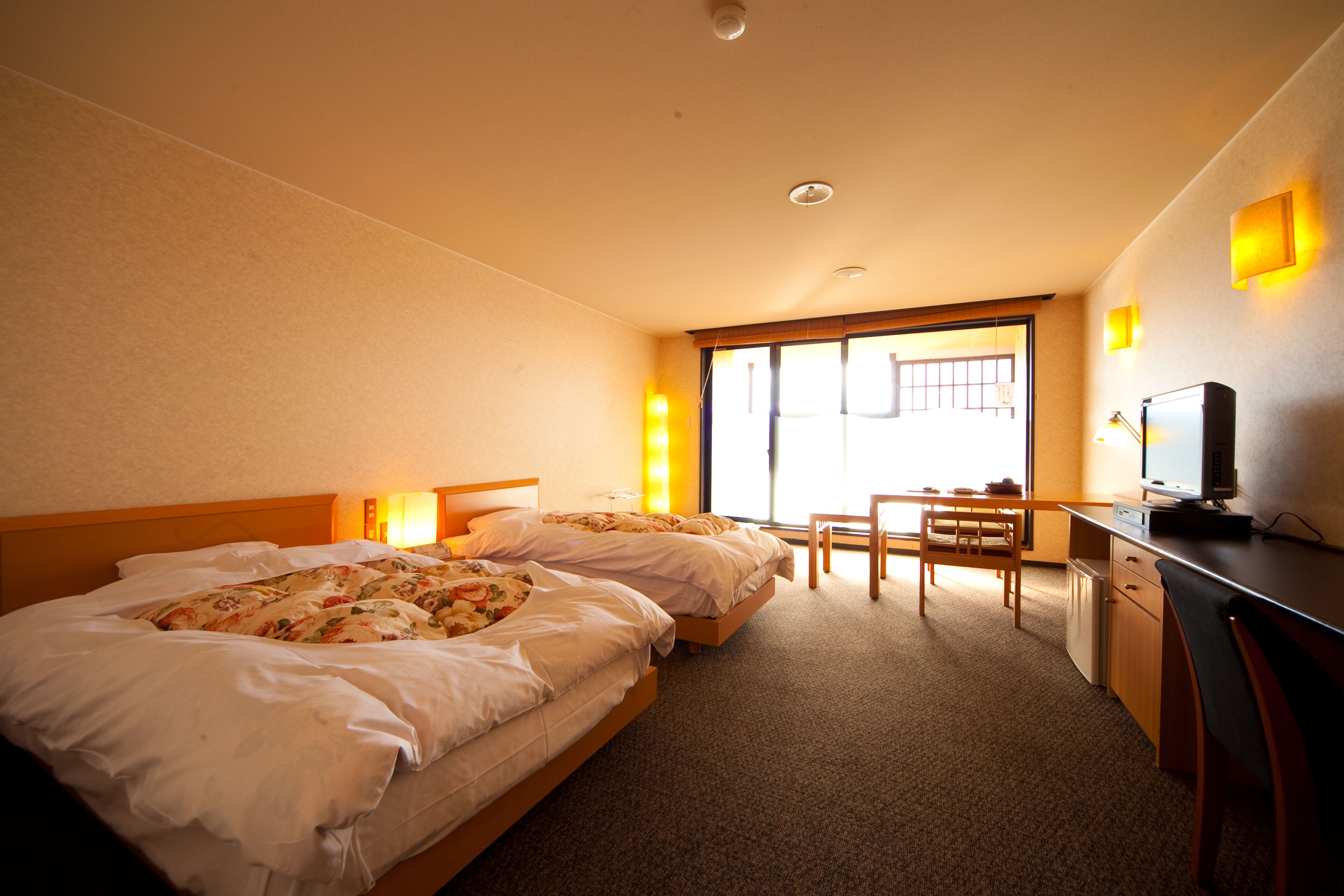 Une chambre d’hôtel avec deux lits, un bureau, une télévision et une fenêtre donnant sur un paysage agréable.