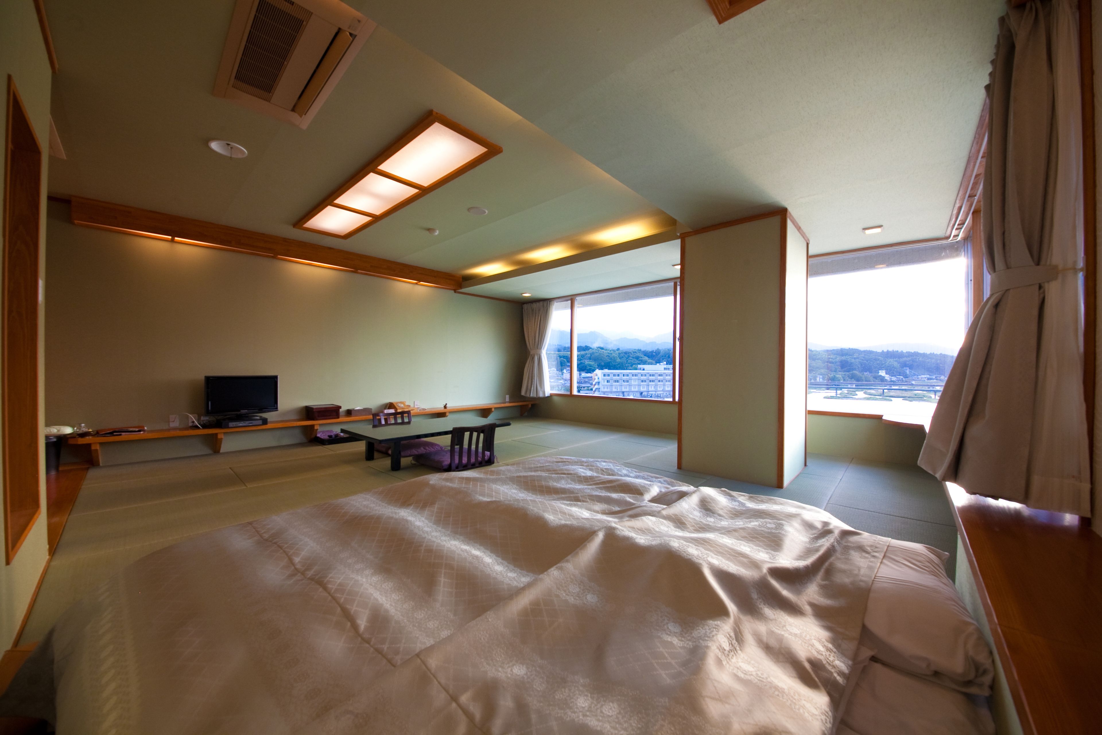A spacious room with a large bed, a television, and a view of the outdoors.