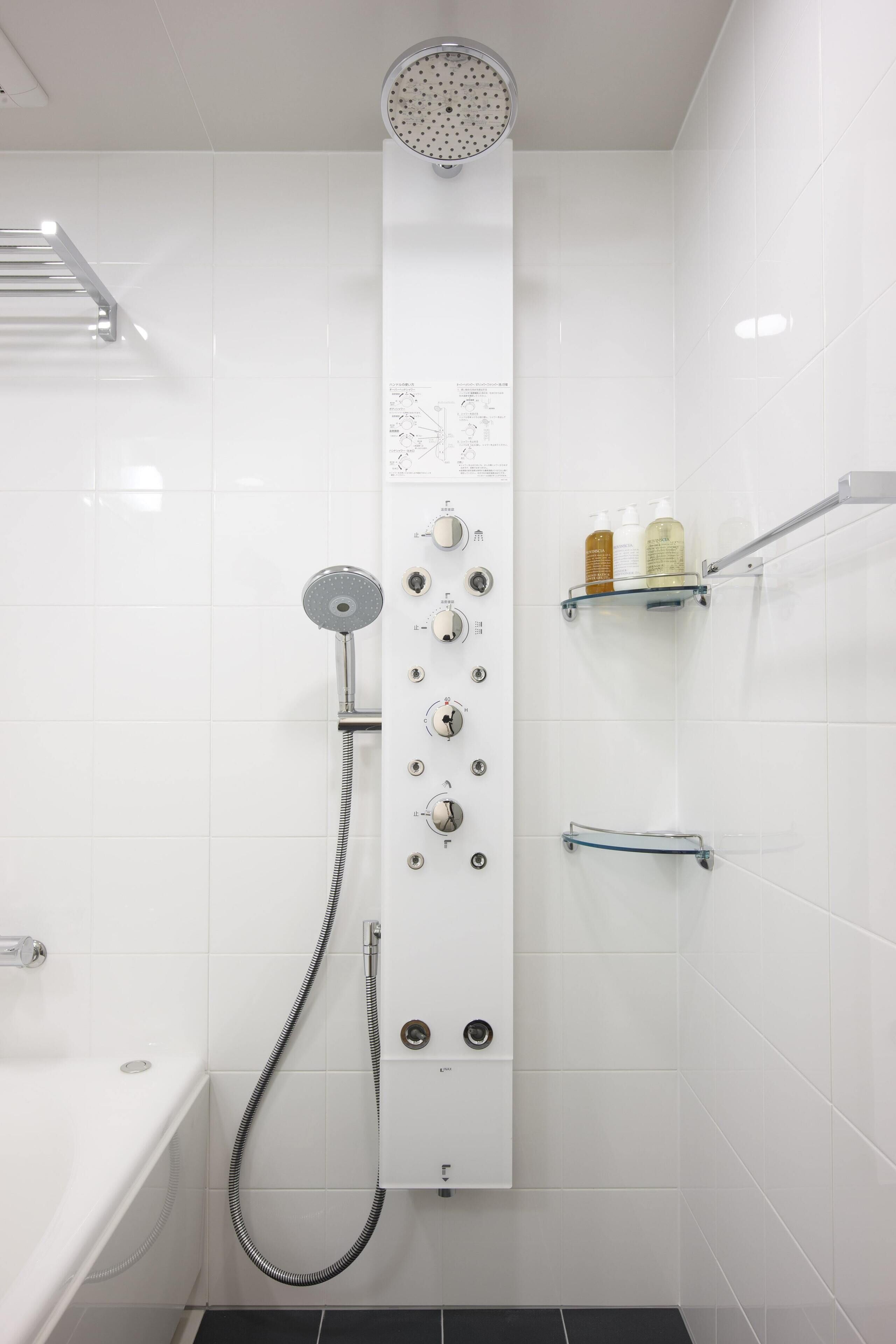 A modern bathroom with a walk-in shower, a bathtub, and a glass shelf with toiletries.