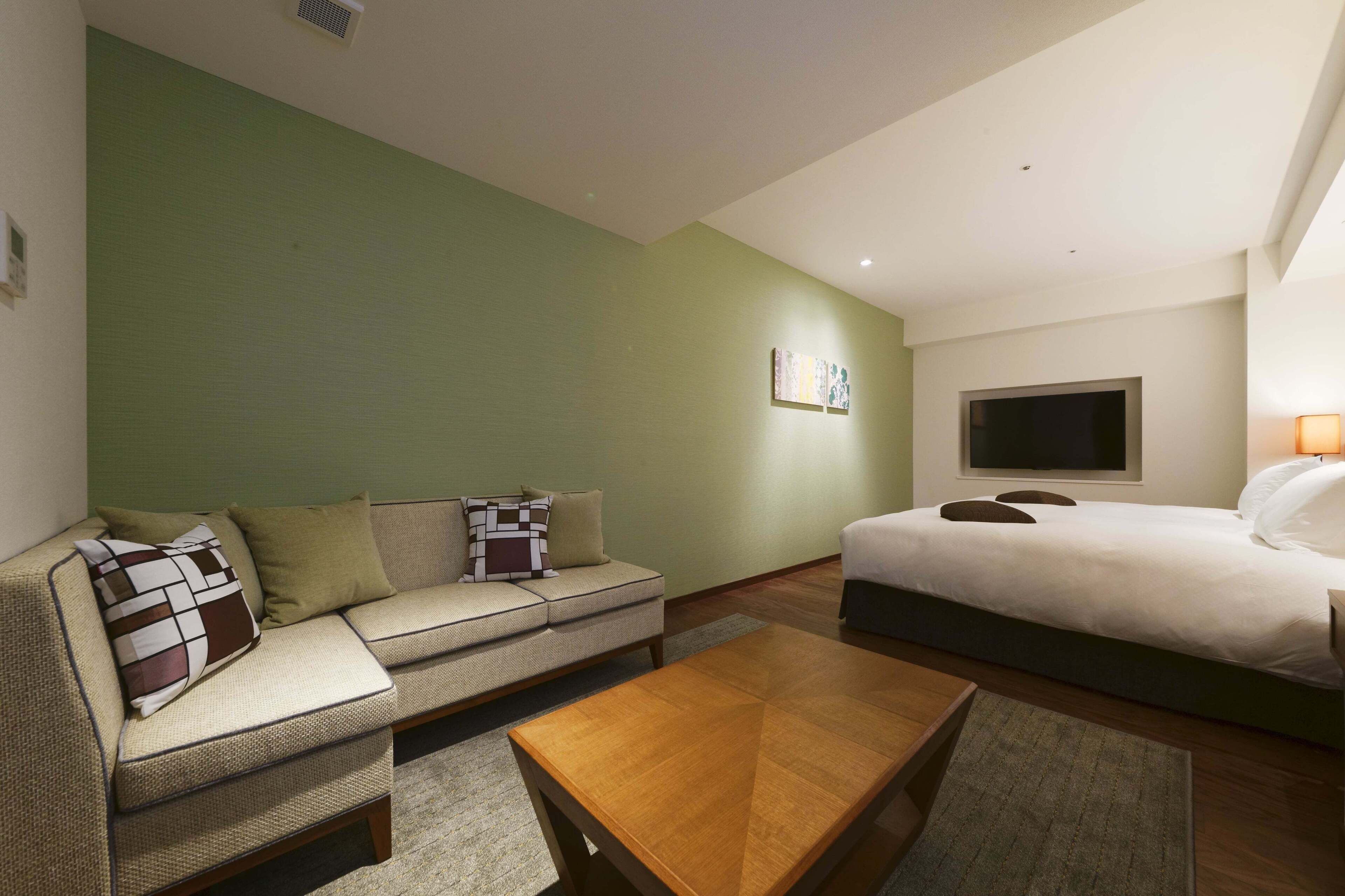 Een hotelkamer met een slaapbank, een bed, een salontafel en een flatscreen televisie.