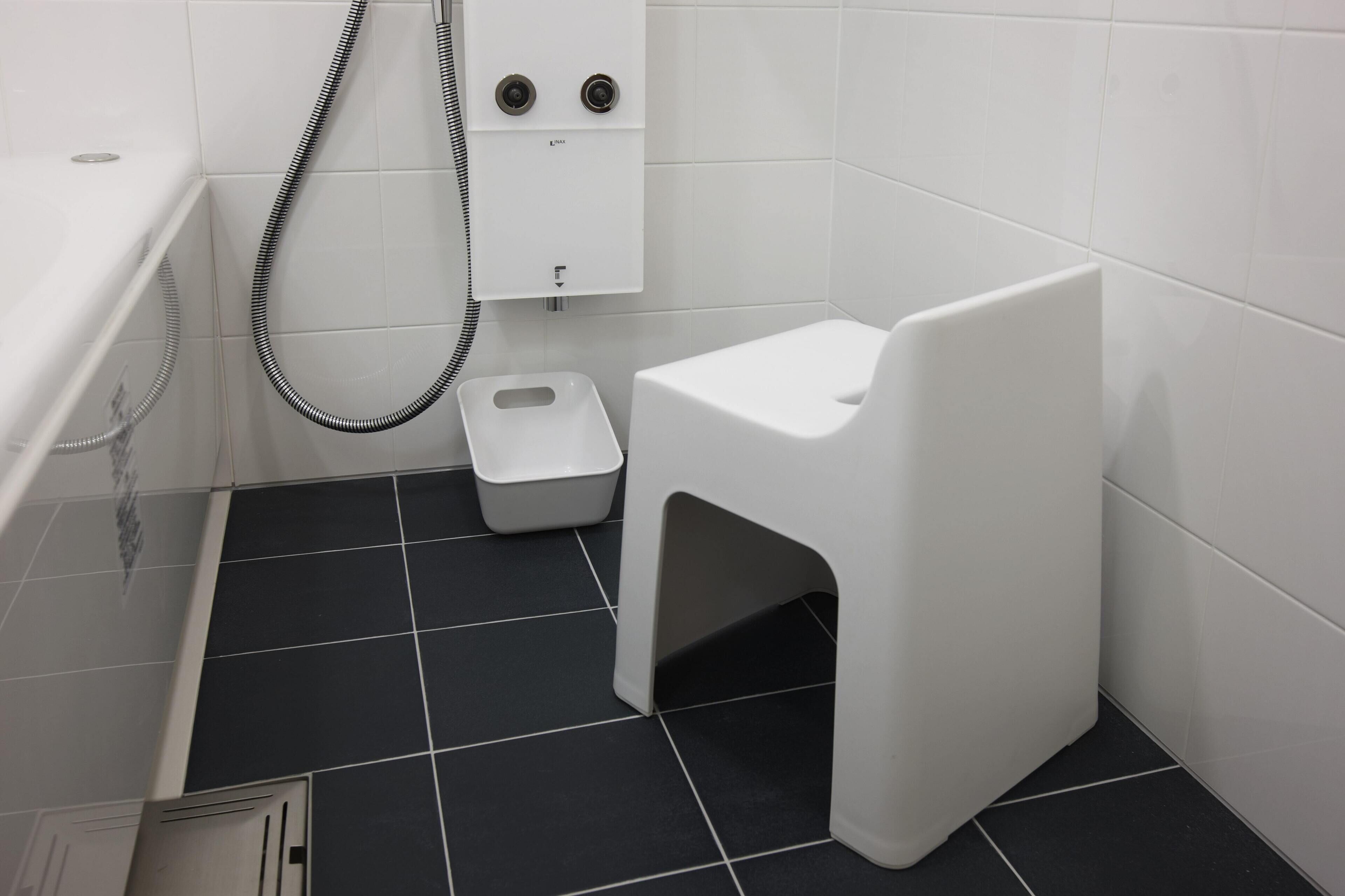 Un baño pequeño con inodoro y bote de basura blancos, y zona de ducha con ducha.