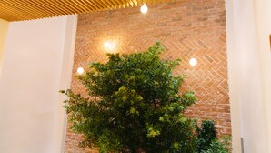 A room with a brick wall, wooden ceiling slats, and a green plant. - Minh Nhung Hotel (1 Bao Loc)