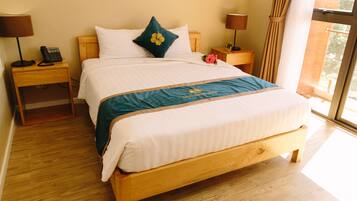 A neatly made bed with a wooden frame and a white and teal bedspread. There are two bedside tables with lamps and a telephone on one.