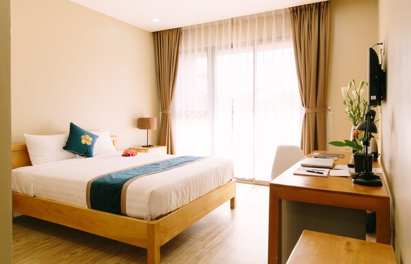 A hotel room with a wooden bed, a desk, a chair, a lamp, and a television. - Minh Nhung Hotel (1 Bao Loc)