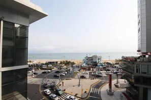 Vista de una zona costera con un estacionamiento, una playa y un edificio con un cartel que dice 'SANDY'S'.