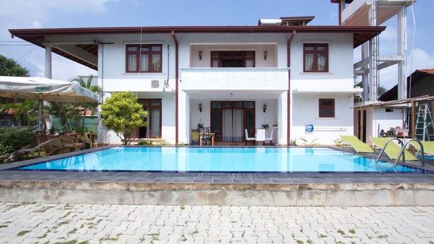 A two-story building with a swimming pool in front. - The Blue Beach Guesthouse (Negombo)