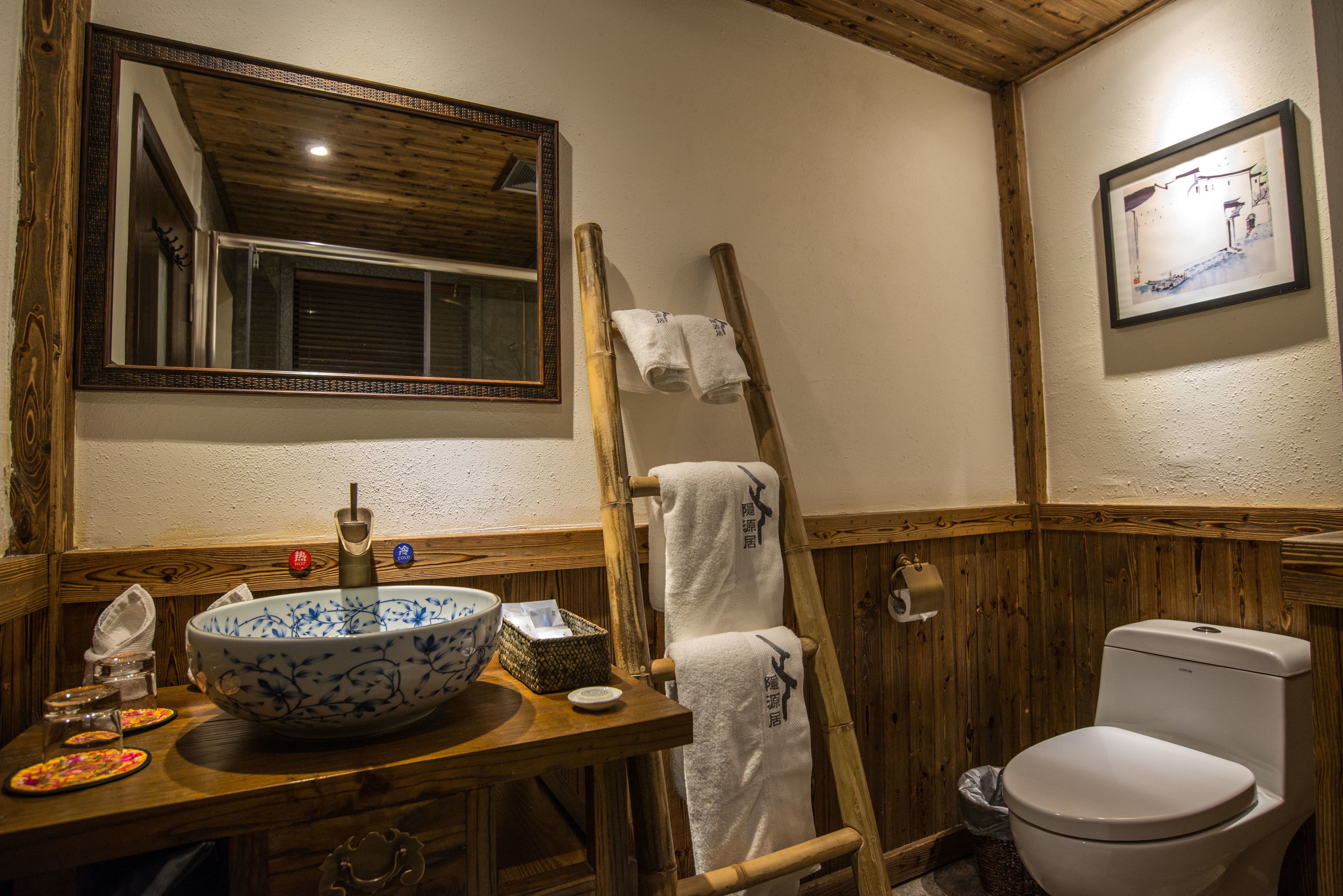 A bathroom with a wooden vanity, a large bowl sink, a toilet, and a mirror.
