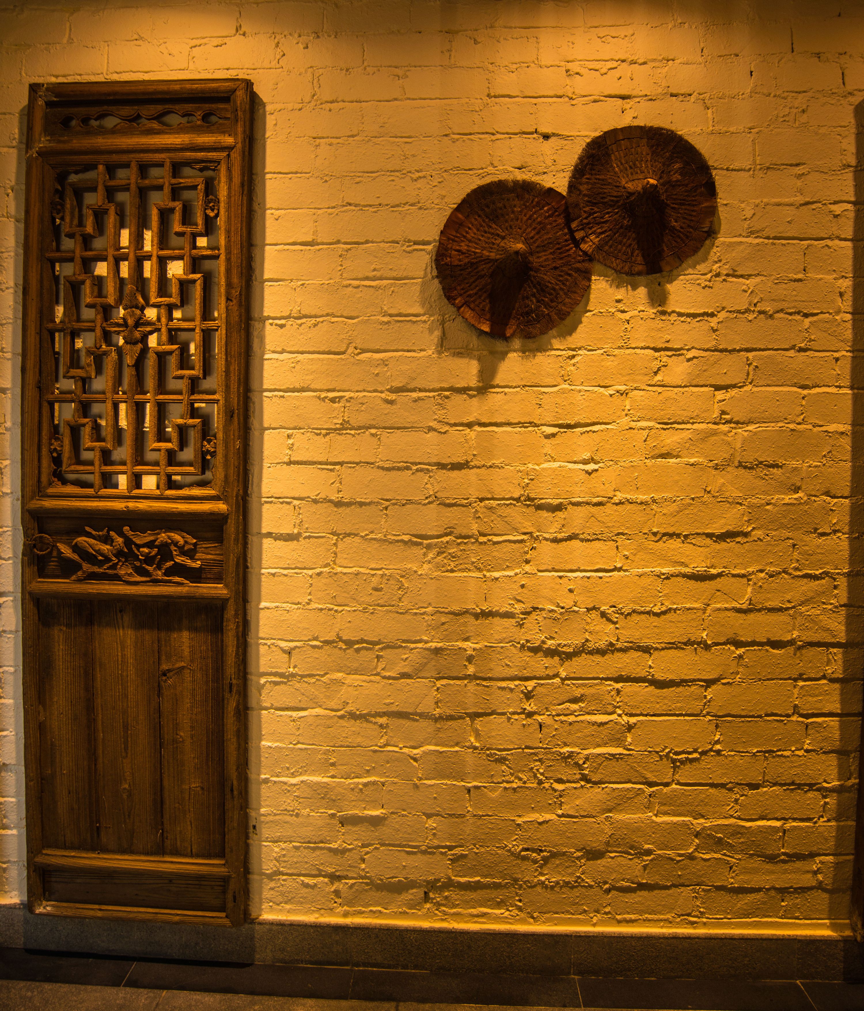 A brick wall with a wooden door and two wall-mounted decorative items.